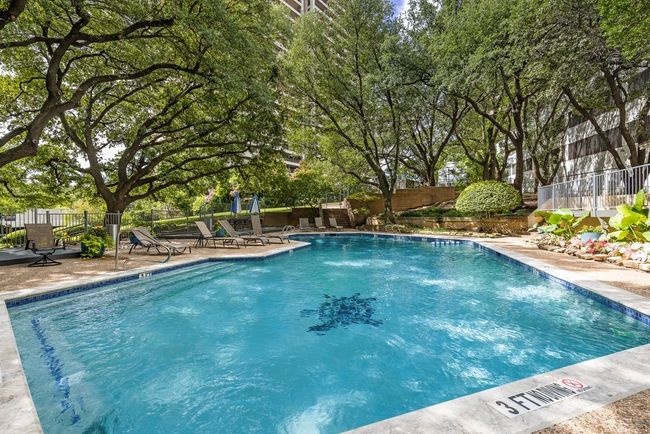 Community pool featuring a patio area and view of wooded area. | Image 22
