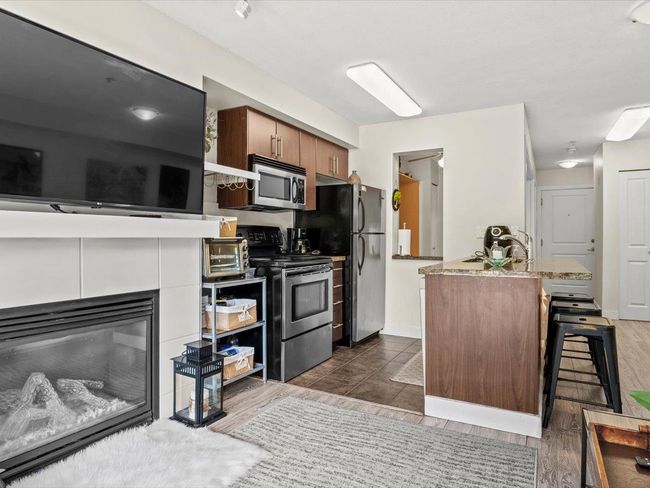 Kitchen featuring stainless steel appliances, a kitchen bar, dark wood-style flooring, and brown cabinets | Image 7