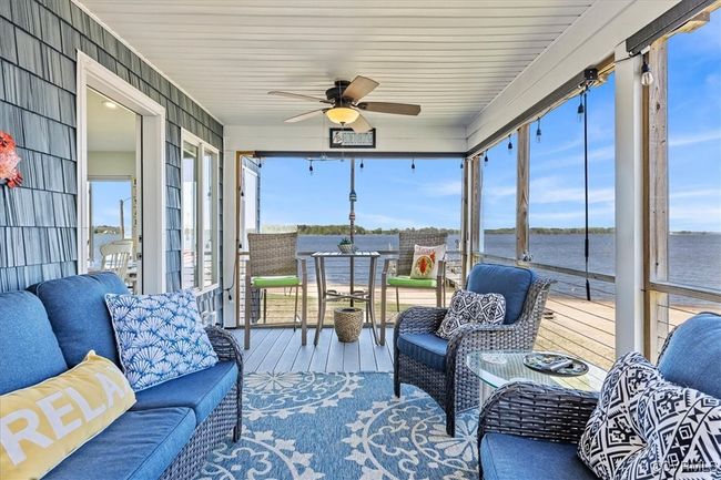 Screened porch off of the large family, greatroom area, featuring a water view, an outdoor hangout area, and ceiling fan | Image 16