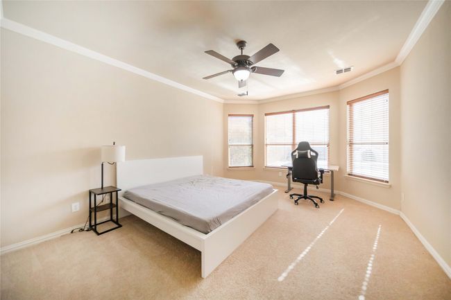 Bedroom with crown molding, carpet, ceiling fan, and an office area | Image 20