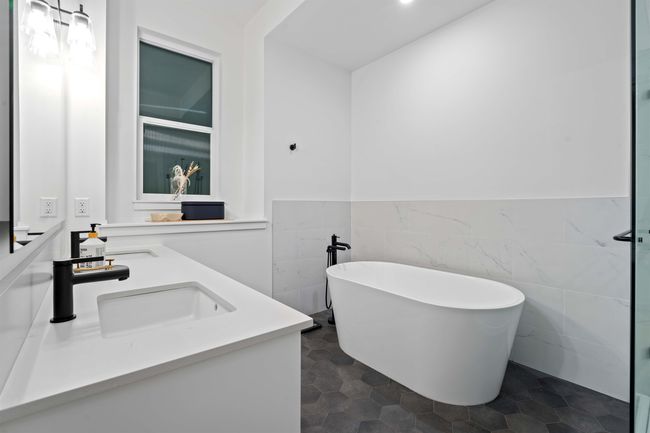 Full bathroom with a freestanding tub, a sink, tile walls, wainscoting, and double vanity | Image 20