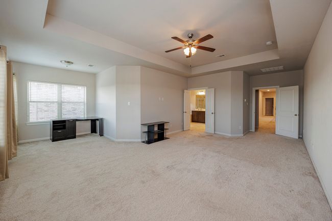 Unfurnished living room with a tray ceiling, ceiling fan, and light carpet | Image 35