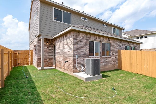 Rear view of house featuring brick siding, central AC unit, a fenced backyard, and a yard | Image 28
