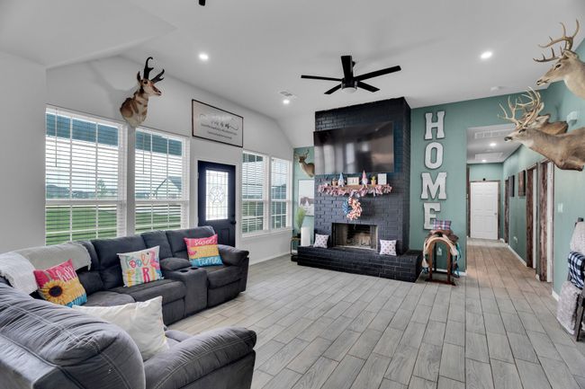 Living room featuring lofted ceiling, ceiling fan, wood finished floors, a brick fireplace, and recessed lighting | Image 8