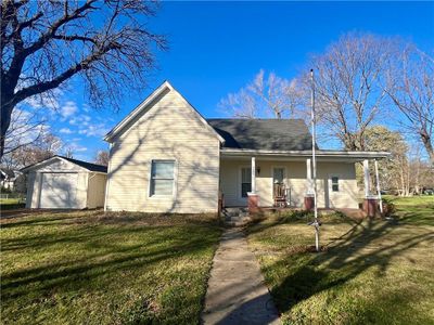 View of front of house featuring a garage, covered porch, an outbuilding, and a front yard | Image 1