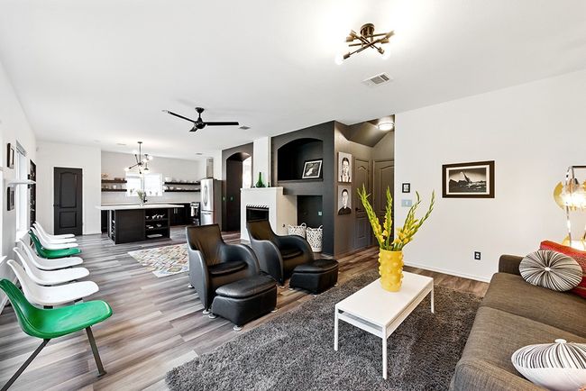 Living area with ceiling fan, wood finished floors, a tiled fireplace, arched walkways, and baseboards | Image 12