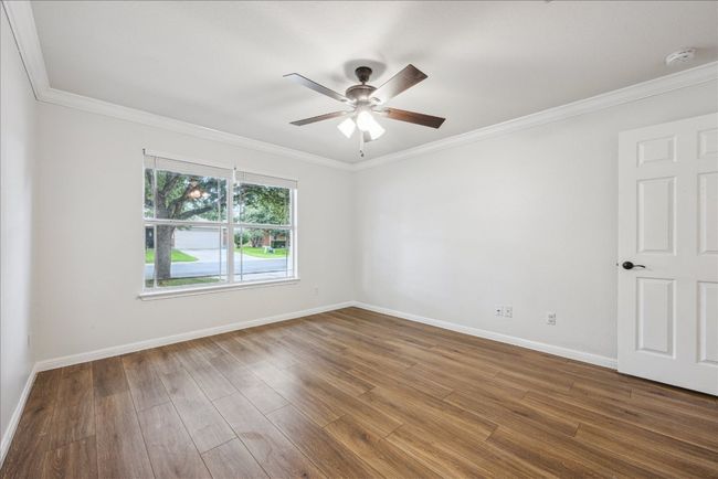 Oversized secondary bedroom with large windows, crown molding, ceiling fan, and closet with sliding doors | Image 25