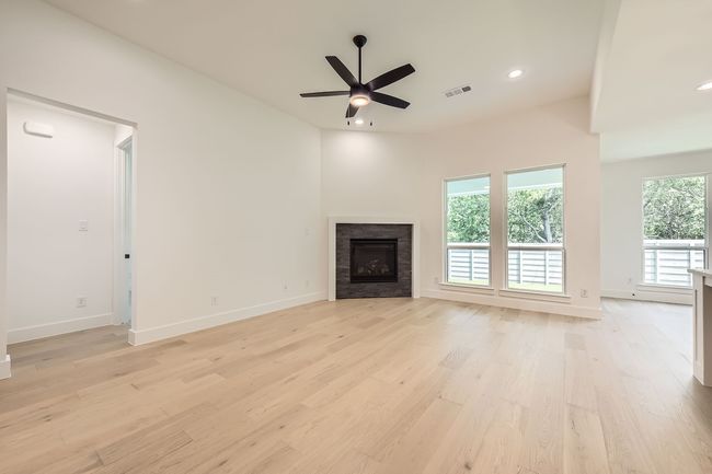 Unfurnished living room featuring light wood finished floors, baseboards, ceiling fan, a fireplace, and recessed lighting | Image 6