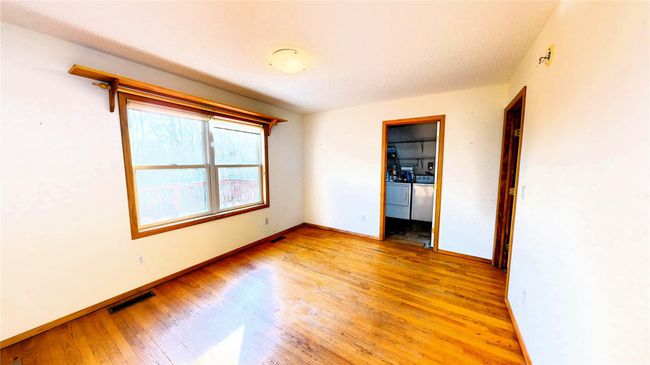 Empty room with washer and dryer, light wood-style flooring, baseboards, and visible vents | Image 14