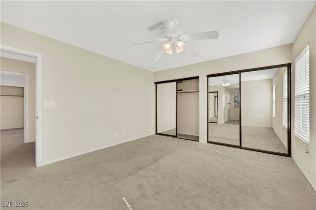 Unfurnished bedroom featuring baseboards, a ceiling fan, multiple closets, and light colored carpet | Image 25