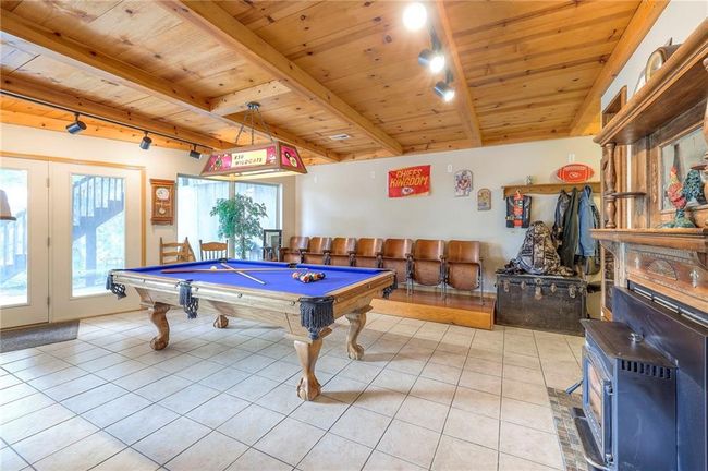 Recreation room featuring rail lighting, a wood ceiling with exposed beams, a wood stove, billiards table, and light tile patterned flooring | Image 37