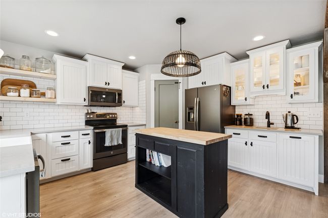 Kitchen featuring stainless steel appliances, white cabinets, open shelves, and wooden counters | Image 13
