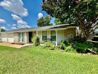 Ranch-style home with a front lawn, covered porch, and a garage | Image 1