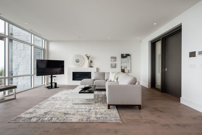 Living room featuring floor to ceiling windows, wood finished floors, a glass covered fireplace, and recessed lighting | Image 10