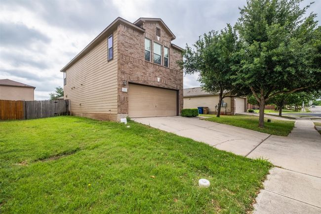 View of home's exterior with fence, an attached garage, a yard, and concrete driveway | Image 5