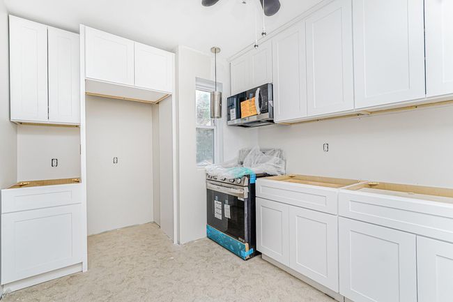 Kitchen featuring appliances with stainless steel finishes, light carpet, white cabinets, ceiling fan, and light countertops | Image 19