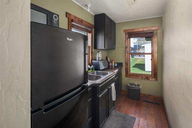 Kitchen featuring dark countertops, dark wood-style flooring, crown molding, and freestanding refrigerator | Image 13