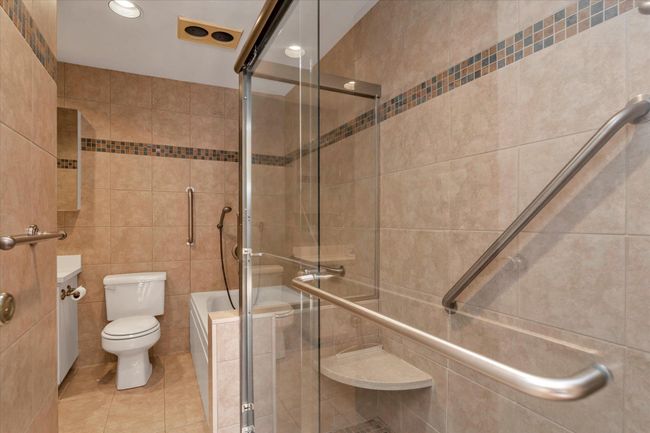 Bathroom featuring a washtub, tile walls, toilet, a stall shower, and tile patterned flooring | Image 19