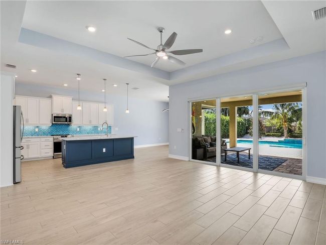 Living room featuring ceiling fan, light hardwood / wood-style floors, a raised ceiling, and sink | Image 11