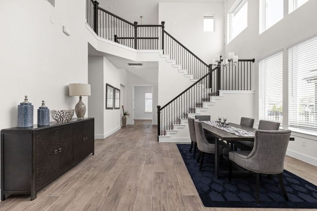 Dining room with a high ceiling, stairway, wood finished floors, a chandelier, and baseboards | Image 10