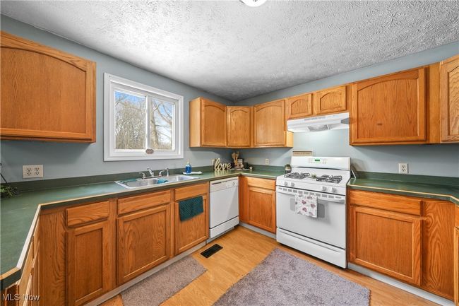 Kitchen featuring white appliances, sink, a textured ceiling, and light wood-type flooring | Image 10