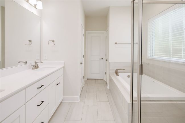 Full bathroom with double vanity, a garden tub, baseboards, and tile patterned floors | Image 12