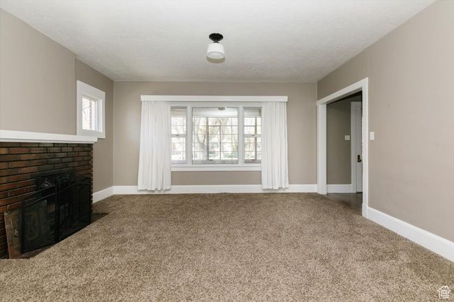 Empty room with dark wood-style flooring, a fireplace, baseboards, visible vents, and a textured ceiling | Image 8