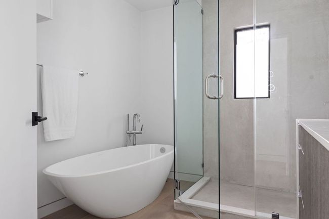 Full bathroom featuring a stall shower, a freestanding bath, and vanity | Image 21