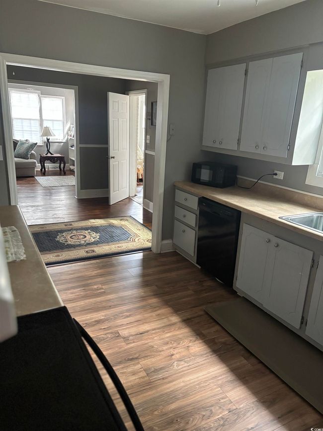 Kitchen with black appliances, a sink, and dark wood finished floors | Image 12