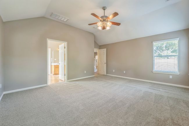Empty room featuring a ceiling fan, baseboards, light colored carpet, lofted ceiling, and visible vents | Image 9