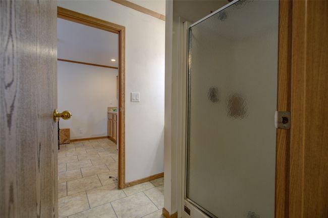 Bathroom with tile patterned flooring, crown molding, baseboards, and a shower stall | Image 5
