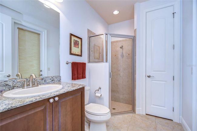 Step into serenity with this elegant bathroom, featuring a sleek granite countertop, modern fixtures, and a spacious glass shower. | Image 27