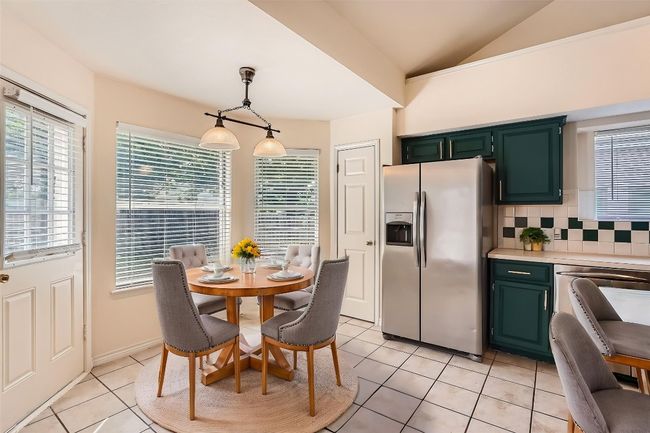 Dining room with light tile patterned flooring and lofted ceiling | Image 8