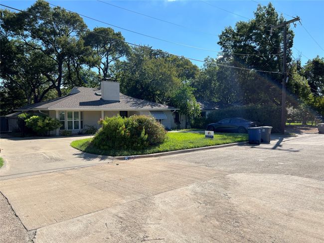 Ranch-style home featuring driveway, a chimney, a front lawn, and view of wooded area | Image 5