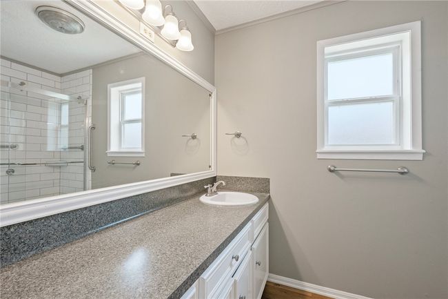 Bathroom featuring vanity, tiled shower, and crown molding | Image 13