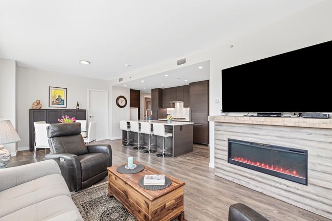 Living area with light wood-style flooring, a glass covered fireplace, visible vents, recessed lighting, and baseboards | Image 13