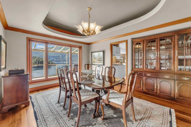 Dining space featuring light wood finished floors, an inviting chandelier, a water view, a tray ceiling, and ornamental molding | Image 17