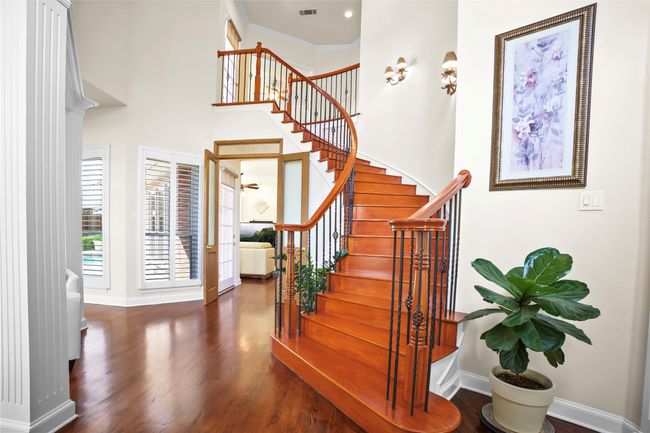 Staircase with wood finished floors and a towering ceiling | Image 4
