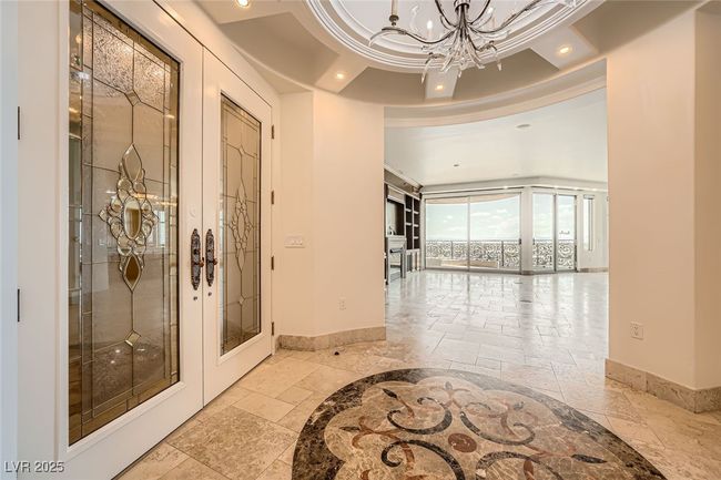 Hallway with stone tile floors, baseboards, french doors, a chandelier, and recessed lighting | Image 6