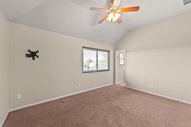 Carpeted empty room featuring lofted ceiling and a ceiling fan | Image 22