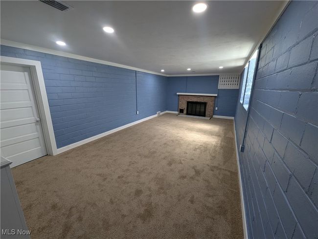 Unfurnished living room featuring carpet flooring, baseboards, visible vents, and a fireplace | Image 26