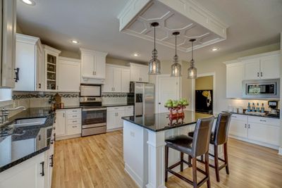 The beautifully updated kitchen features a new stove, microwave, a large center island, a spacious pantry, and abundant counter and cabinet space. | Image 3