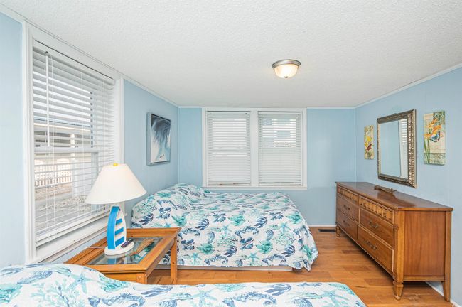 Bedroom with light wood-style floors, a textured ceiling, and ornamental molding | Image 15