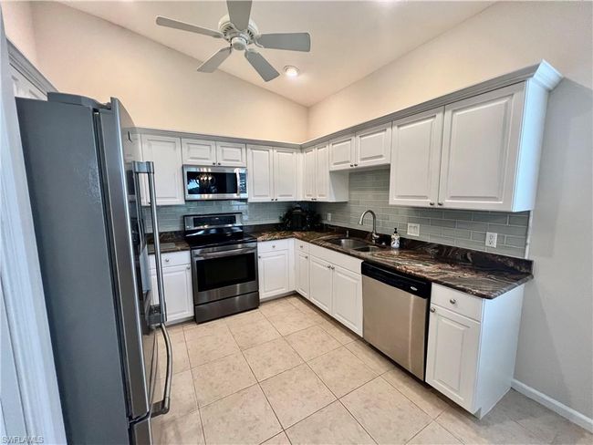 Kitchen with white cabinets, subway tile backsplash, granite counter and stainless steel appliances | Image 9