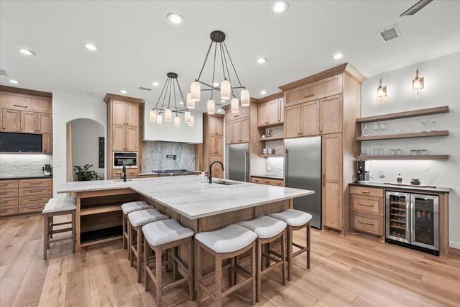 Designed for gatherings big or small, this kitchen island includes built-in wine storage, bar seating, and a separate beverage fridge. | Image 15