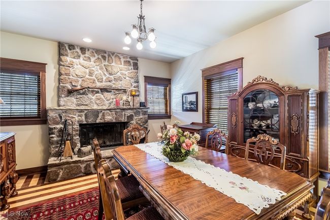 Dining space featuring a healthy amount of sunlight, a stone fireplace, baseboards, and an inviting chandelier | Image 18