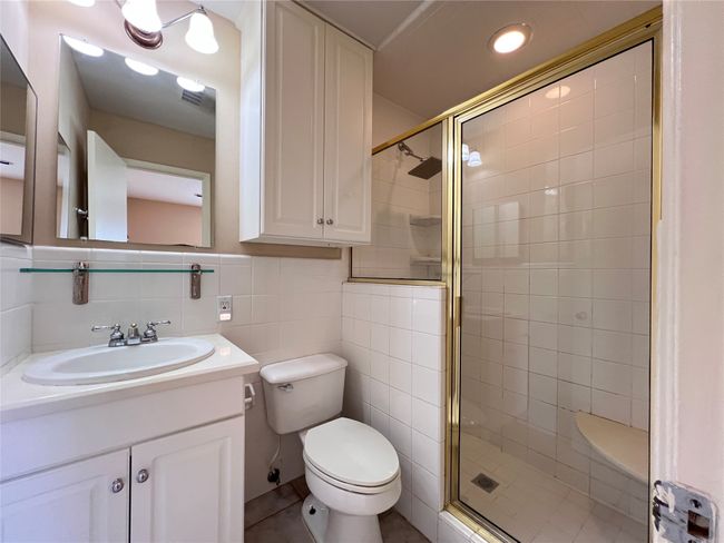 Full bathroom with a shower stall, vanity, and tile walls | Image 5