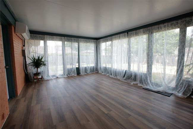 Unfurnished sunroom with a wall mounted air conditioner, wood finished floors, and plenty of natural light | Image 28