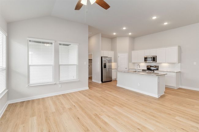 Kitchen featuring stainless steel appliances, light wood finished floors, a sink, and white cabinetry | Image 11