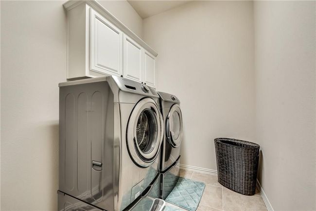 Washroom featuring washing machine and dryer, cabinet space, baseboards, and light tile patterned flooring | Image 7